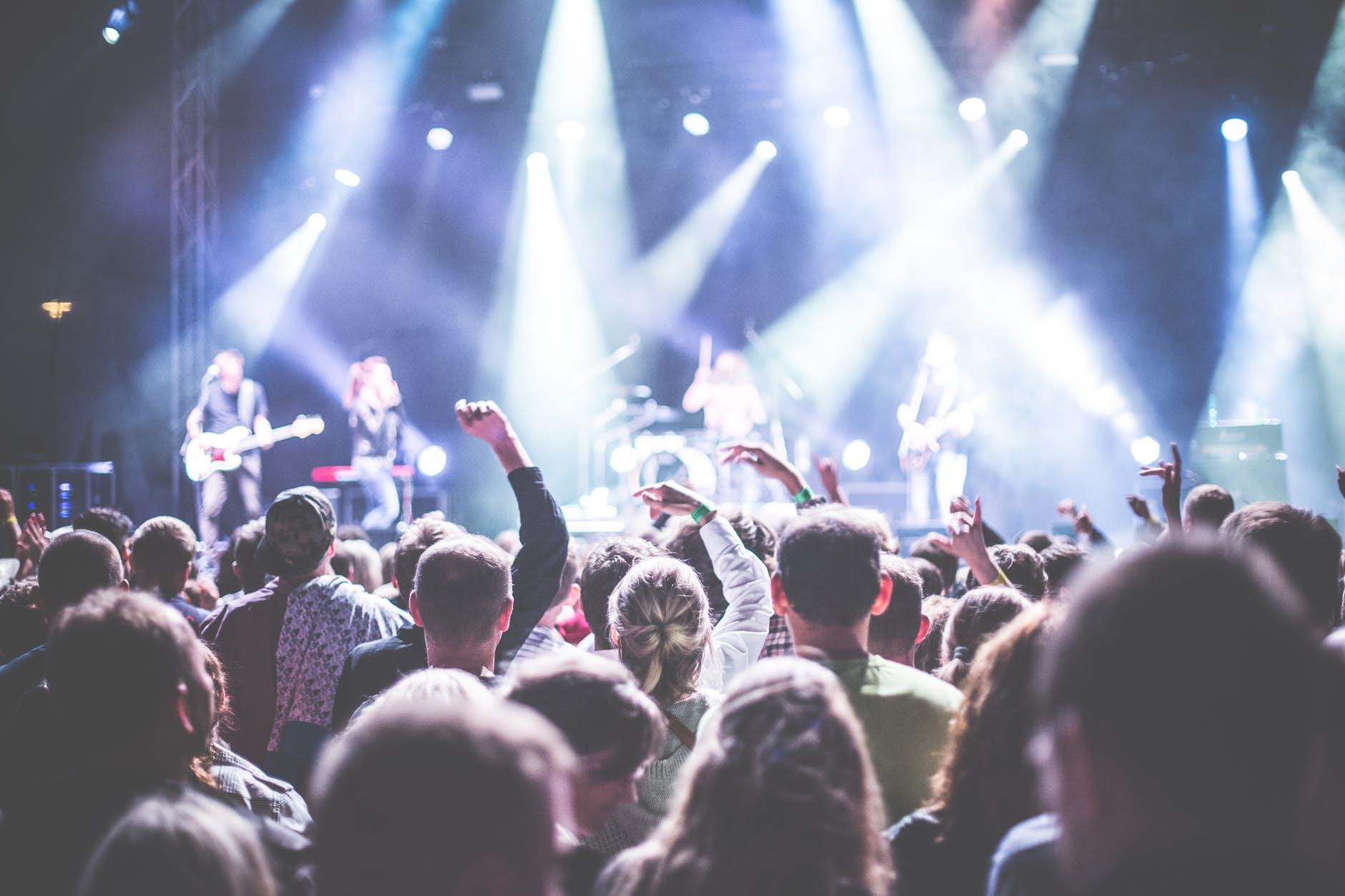 A packed concert crowd under bright stage lights